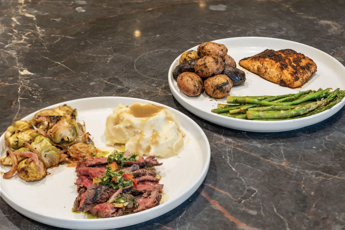 Chef-prepared plates with grilled salmon, herbed potatoes, asparagus, and seared steak with chimichurri at Chelsea Manor Recovery